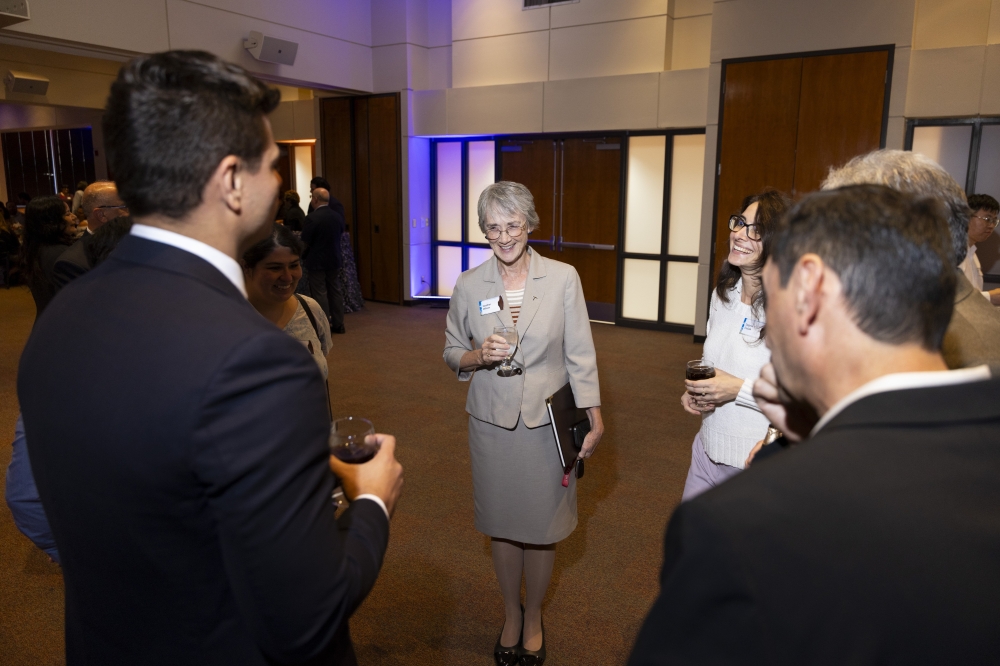 Attendees stand in a circle and converse during a UTEP reception.